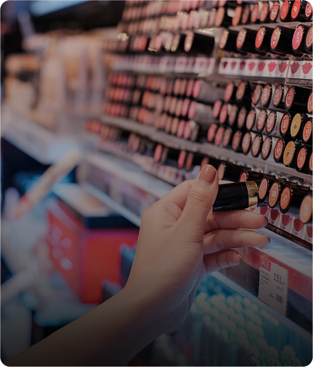 A hand picking a lipstick from a cosmetics wall with a digital price label