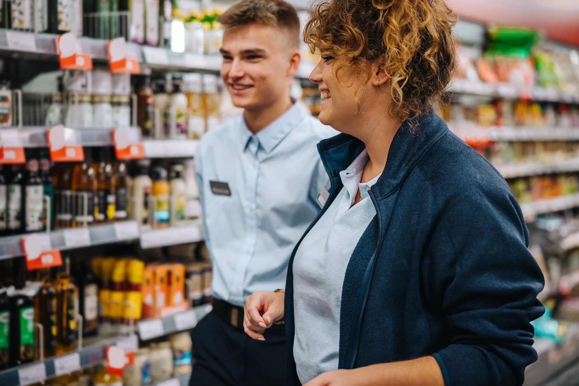 Two store staff walking a grocery aisle fitted with electronic shelf labels
