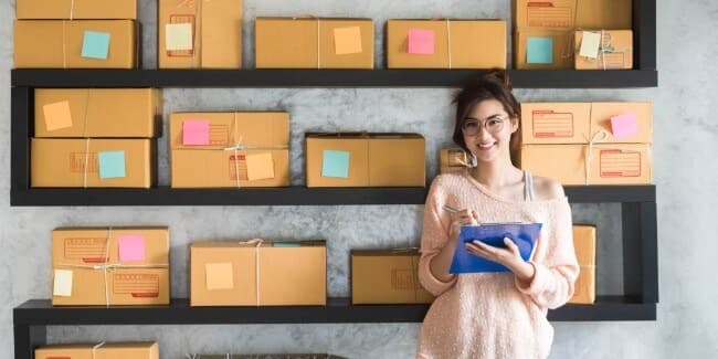 A worker with a clipboard in front of shelves of parcels